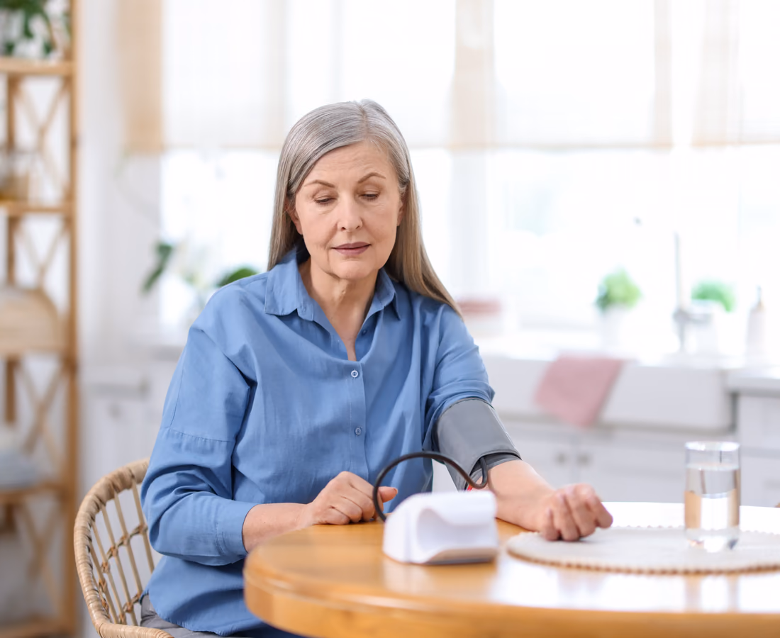 An older patient taking a blood-pressure reading at her kitchen table
